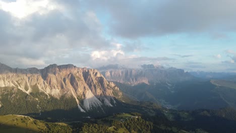 wide drone shot of dolomites mountains and some forest around that area, italy