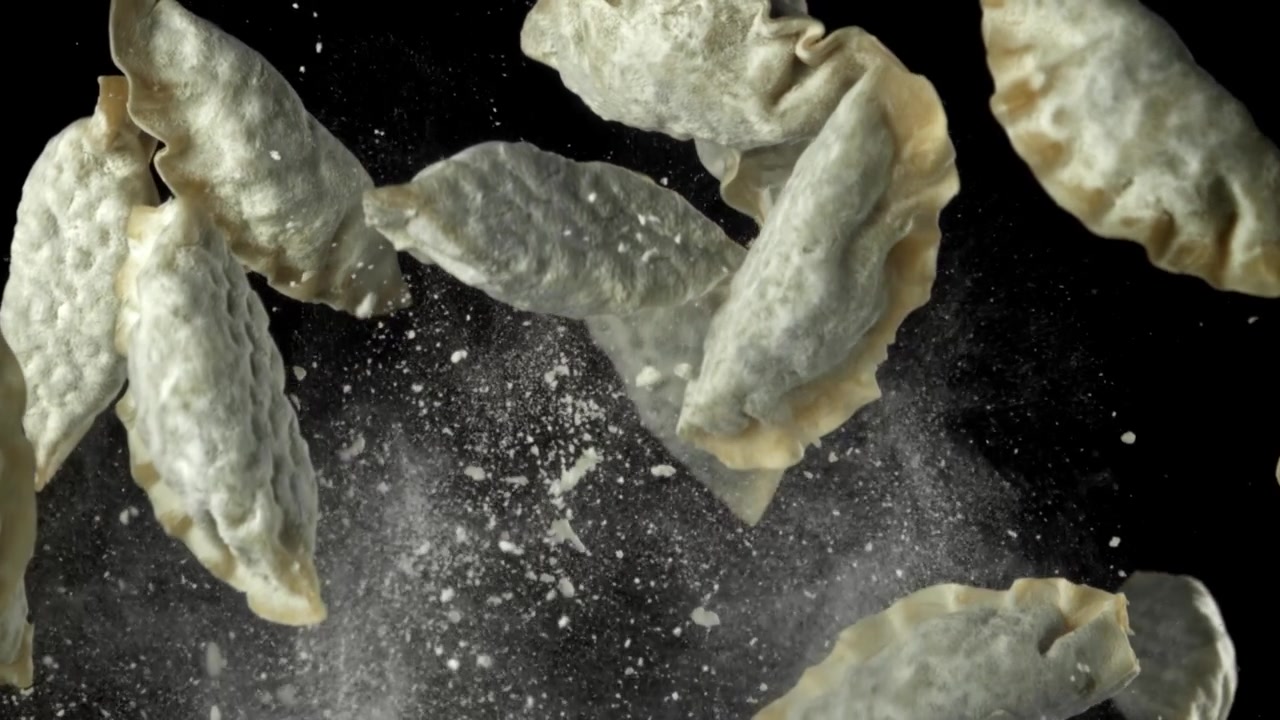 Dumplings Falling with Flour on Black Background in Slow Motion