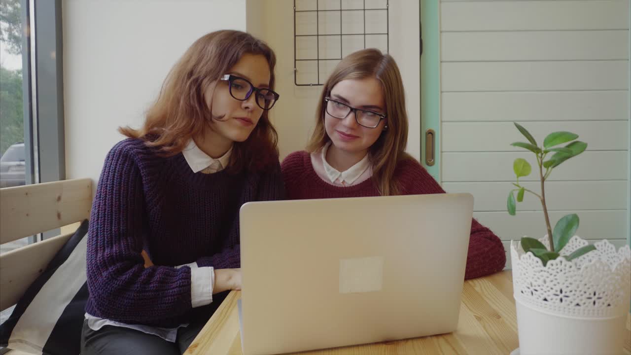 dos mujeres jóvenes estudiando juntas en un café