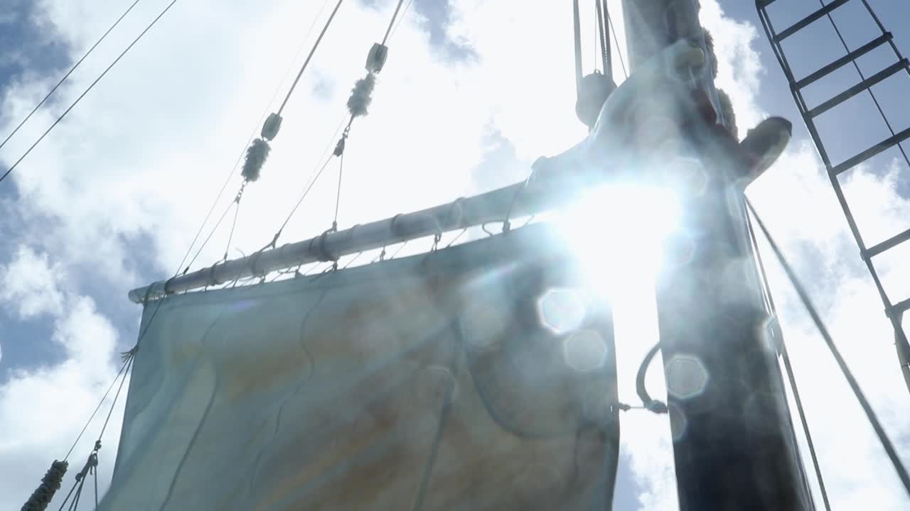 Dropping a sail with the sun shining between the sail and the mast.