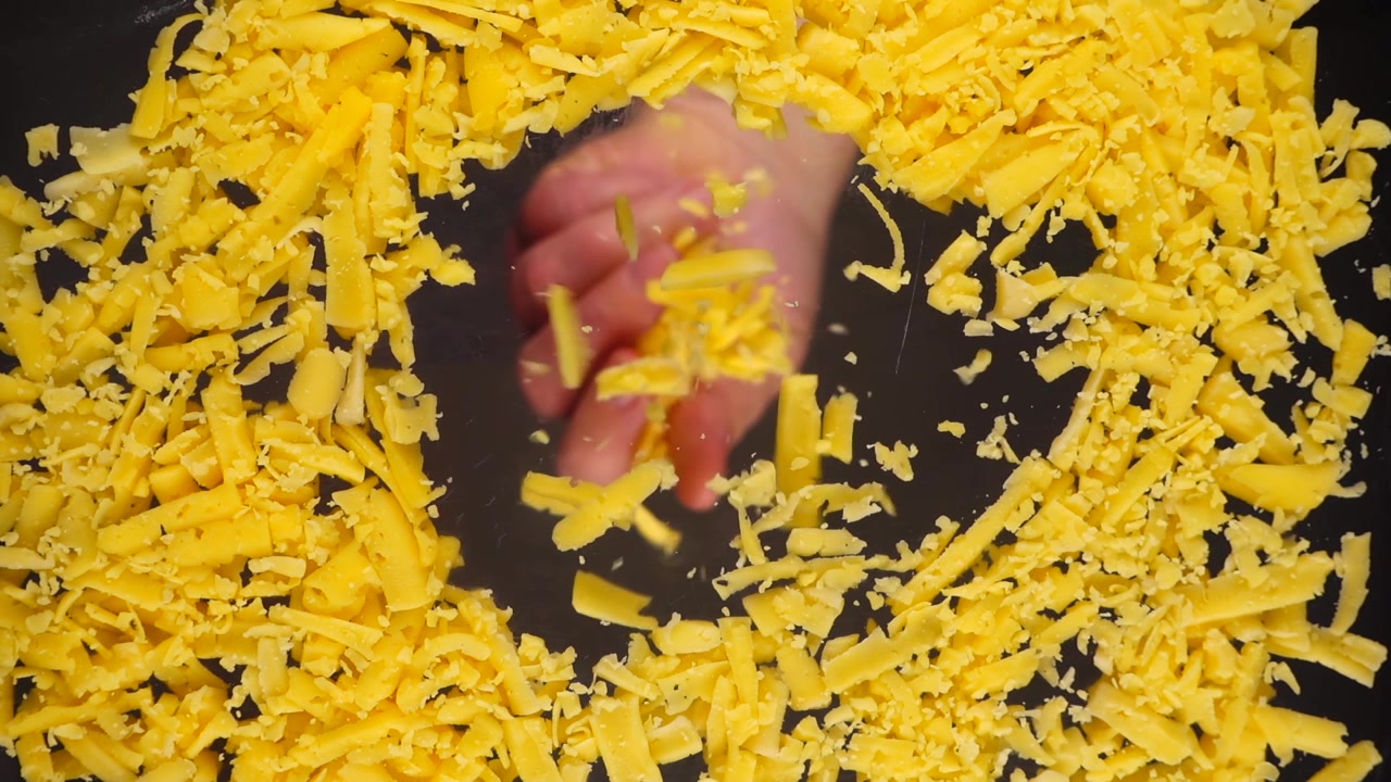 Il formaggio grattugiato viene versato su una superficie di vetro. Vista dal basso