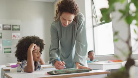 video of happy caucasian female teacher explaining lesson to african american boy