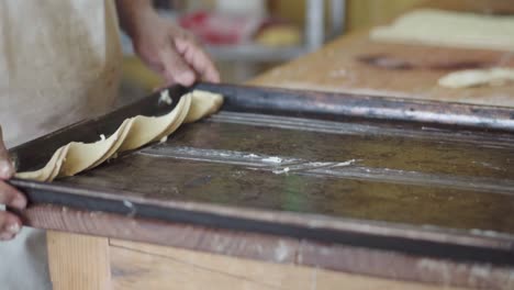 el pastelero arregla cuidadosamente las piezas de masa en una hoja de hornear, preparándose para hornear