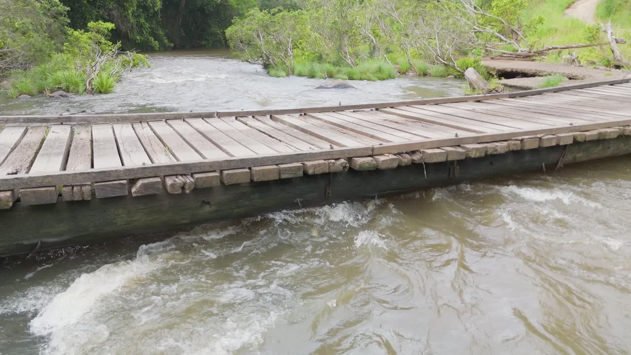 River flows swiftly beneath a wooden bridge