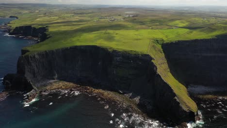 Cliffs-of-Moher-landscape-along-Ireland-Atlantic-coast,-high-aerial-pull-away