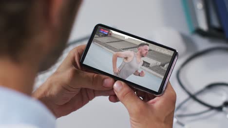 compuesto de un médico masculino viendo un evento de atletismo en un teléfono inteligente