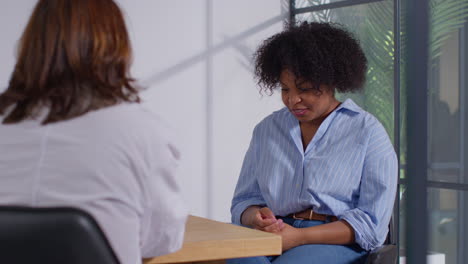 woman meeting with doctor or oncologist wearing white coat to discuss treatment for breast cancer in hospital clinic