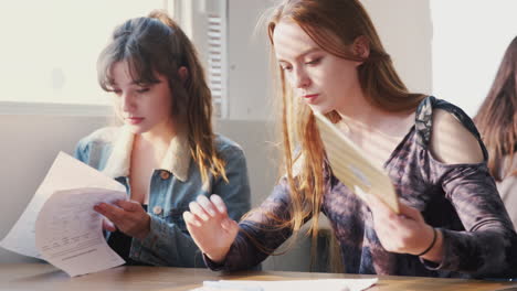 dos estudiantes universitarias sentadas en un escritorio usando una tableta digital en el aula