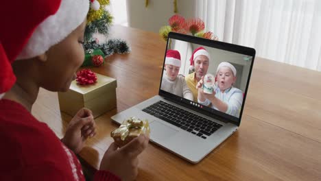 Mujer-Afroamericana-Con-Sombrero-De-Santa-Usando-Una-Computadora-Portátil-Para-Una-Videollamada-Navideña-Con-La-Familia-En-La-Pantalla