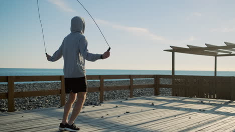 hombre saltando la cuerda en un muelle de la playa