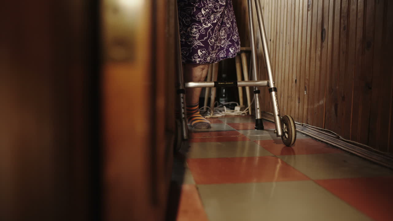 anciana haciendo esfuerzos para caminar alrededor de la casa con un caminante