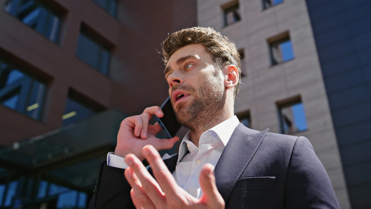 Un avvocato serio parla al telefono in vivavoce in un quartiere commerciale, primo piano. Uomo che chiama