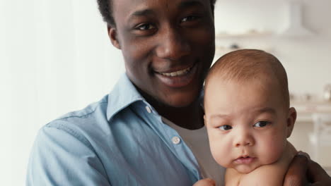 a smiling african american father holds his baby