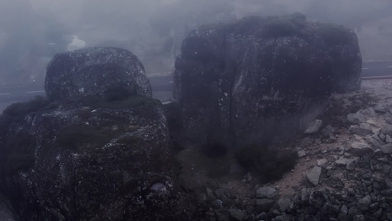 Enormi massi di granito e aspre formazioni rocciose emergono attraverso una fitta nebbia nella Serra da Estrela, Portogallo, rivelando un aspro paesaggio geologico e texture erose in un ambiente ad alta quota
