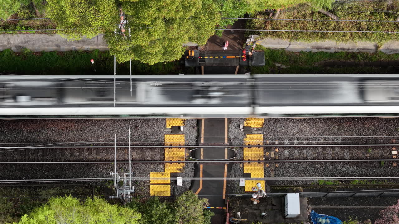 Aerial drone view of a train moving through the Arashiyama train station, Kyoto, Japan in daylight