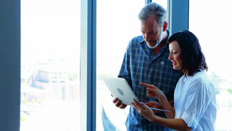 ejecutivos masculinos y femeninos usando computadora portátil cerca de la ventana