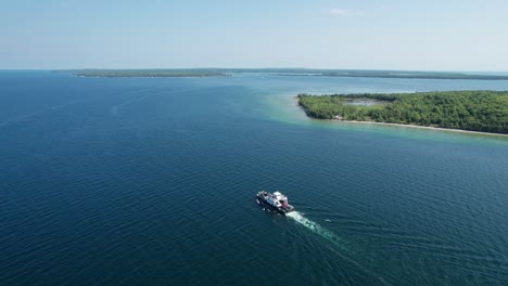 Toma-De-Drone-Que-Muestra-Un-Ferry-Con-Autos-Y-Personas-Dirigiéndose-A-Una-Isla.