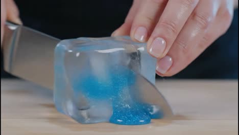 cutting an ice cube with blue liquid inside