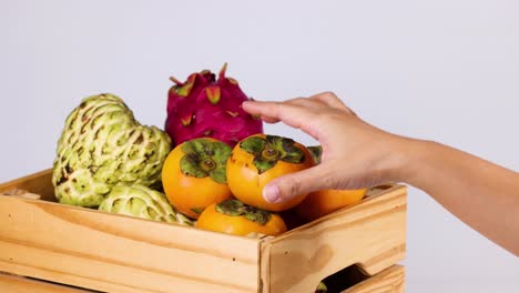 la mano interactúa con el caqui en una caja de madera