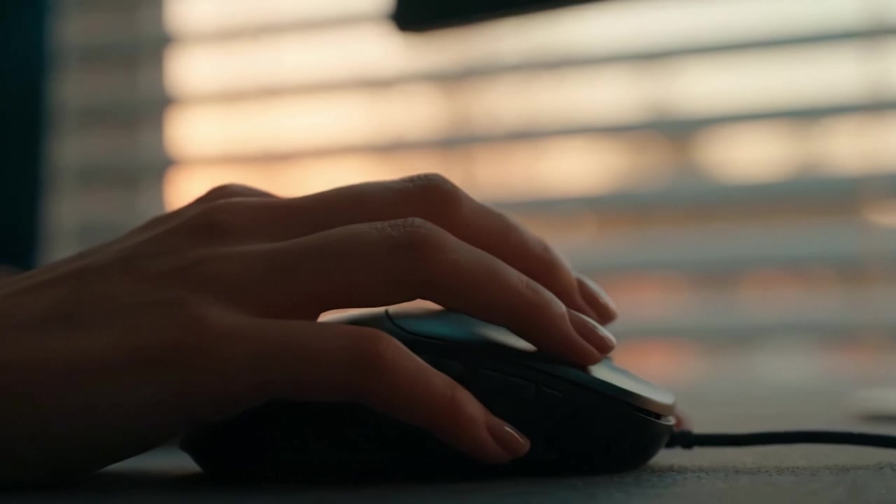 A Close-Up View of a Hand on a Computer Mouse with Blurred Background, Highlighting Focus on Digital Interaction and Technology at Sunset