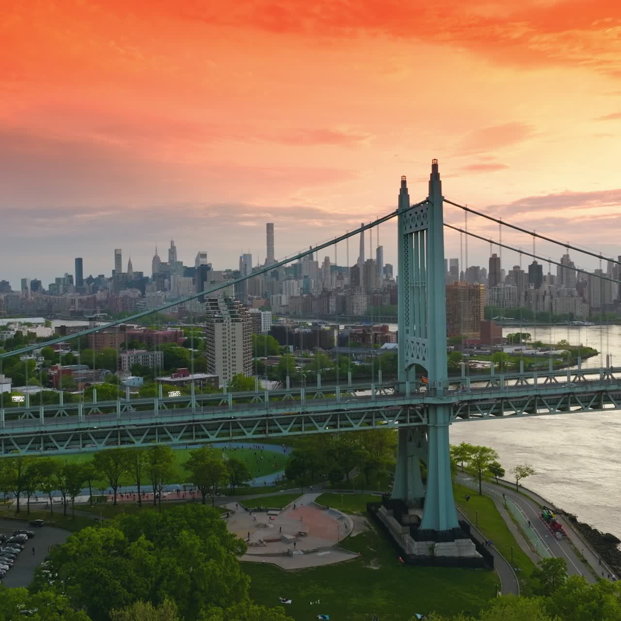 Magnificent light blue bridge with moving transport. New York skyline of skyscrapers under the pink orange sky