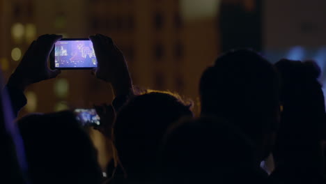 hombre espectador grabando video con zoom del escenario y pantalla grande a través de un teléfono inteligente en un concierto de música al aire libre