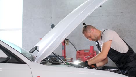 auto mechanic inspecting car engine in a garage