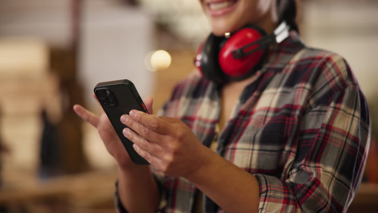 Woman using phone in a carpentry shop
