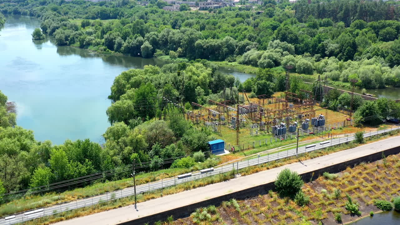 Modern solar power farm among beautiful summer nature. Blue solar panels on the bank of the river. Production of clean energy. Aerial shot.