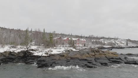 winter scenery on the north shore of lake superior. snowy cottages and lodgings on forested landscape in beaver bay, minnesota. wide drone shot