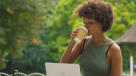 Mujer-Joven-Al-Aire-Libre-En-El-Parque-Sentada-En-Un-Banco-Trabajando-En-La-Computadora-Portátil