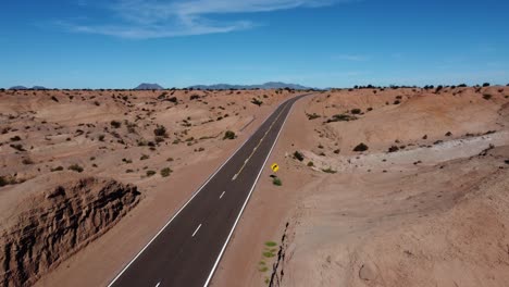 aerial follows clean, clear highway through red rock badland landscape