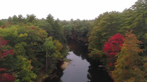 Aerial-Foggy-river-with-autumn-foliage-pull-back-and-rise-with-car-driving-by-on-road