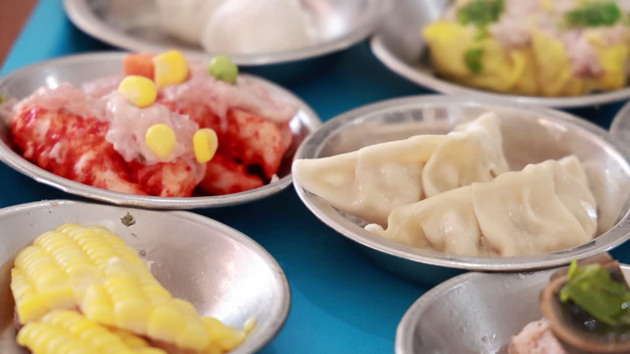 una vibrante exhibición de diversos platos de dim sum en una mesa azul, mostrando el arte culinario tradicional tailandés en la iluminación natural