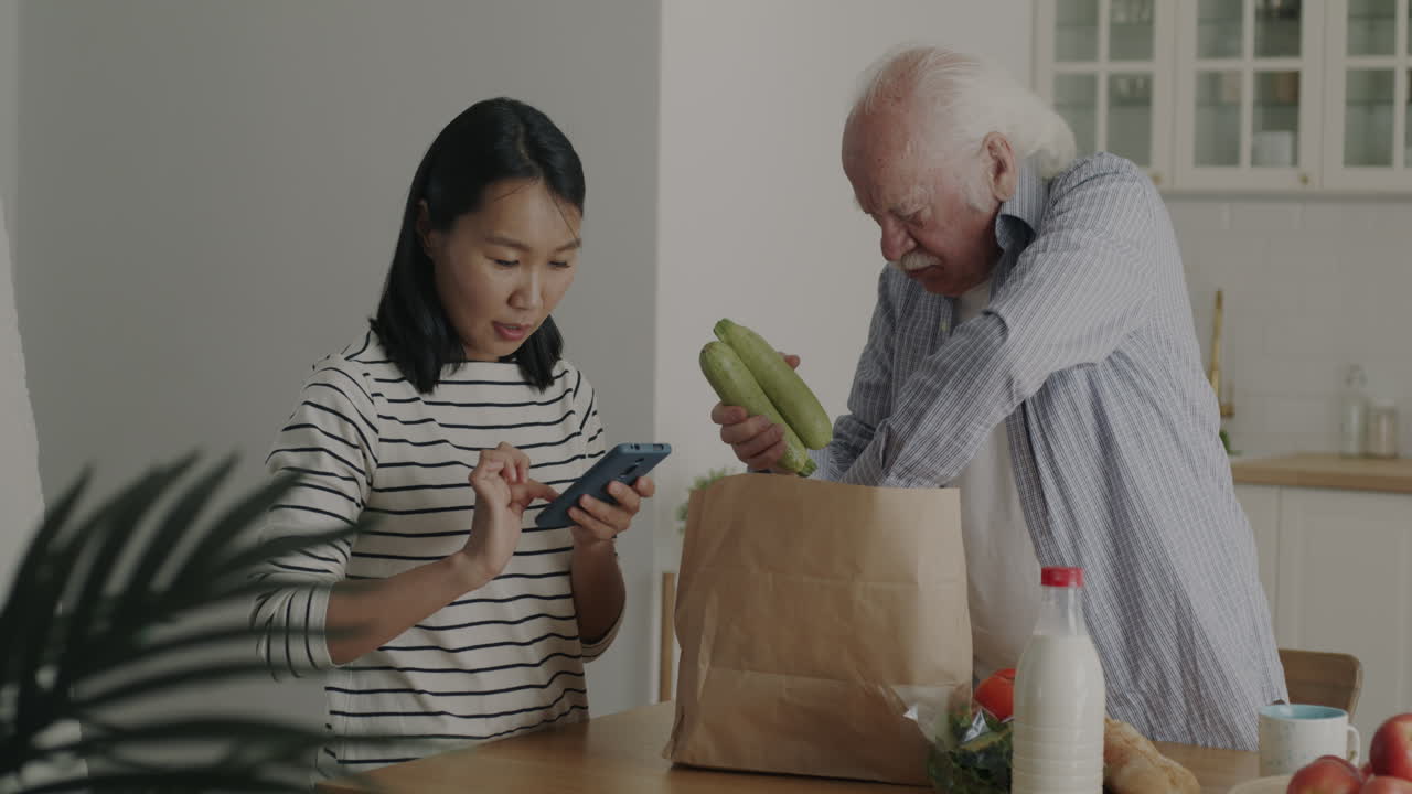 Elderly Man and Young Woman Checking Online Grocery Order