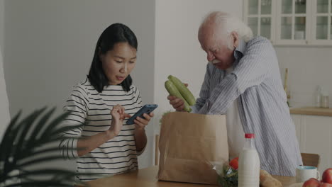 elderly man and young woman checking online grocery order