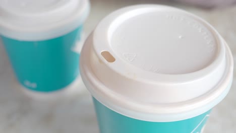 two teal coffee cups with white lids