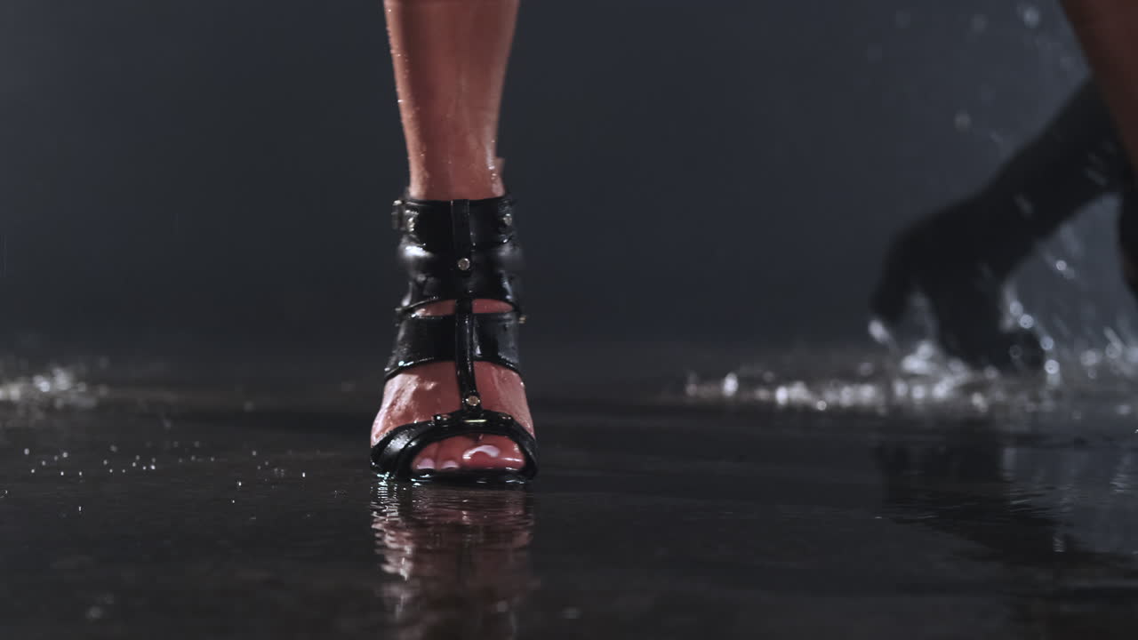las piernas de la mujer en tacones altos caminando bajo la lluvia