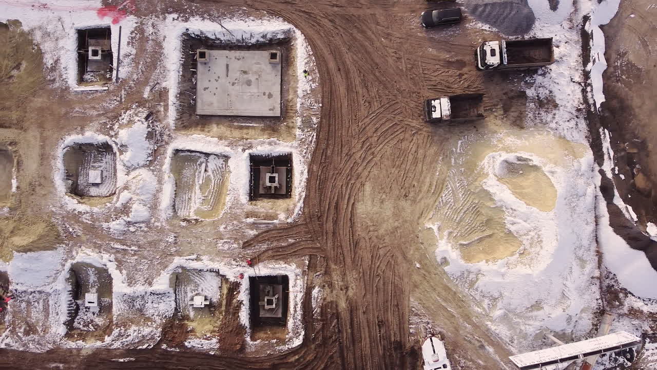 Aerial flight over a new construction site with heavy machinery and people building real estate