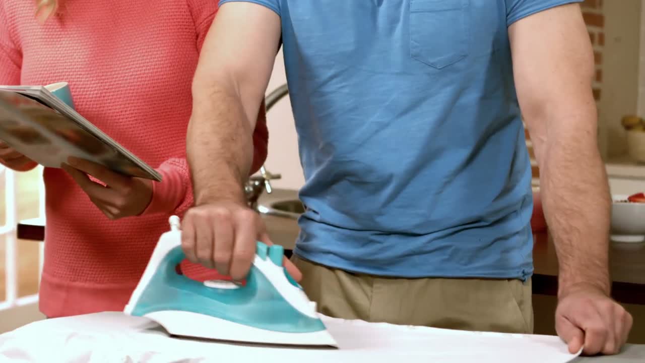 Man ironing while woman reading