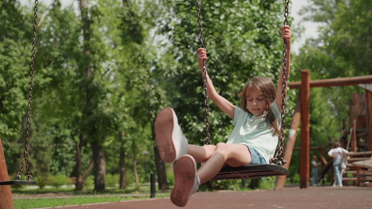 Una niña joven juega delicadamente en un columpio del parque. Disfruta de movimientos suaves, balanceándose con energía y cuidado entre los árboles y la luz del sol.