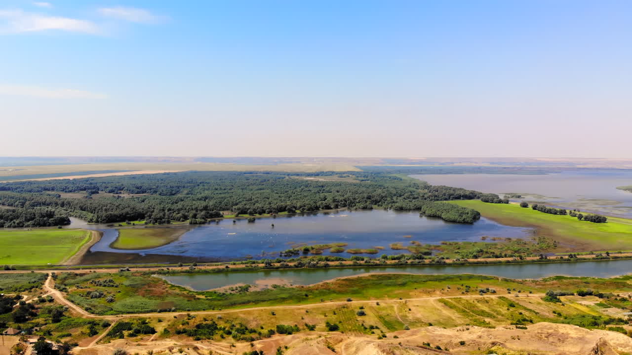 Aerial drone view of a village among greenery in Moldova. Lake and green hills. Panorama view. Sunny day