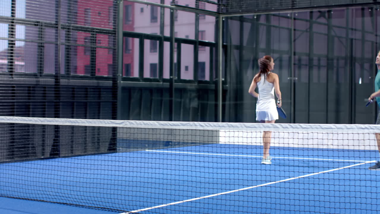 Woman playing padel tennis on indoor court, focused and ready for action