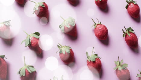 composition of spots of light over strawberries on pink background