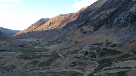 Sunlit-mountain-valley-with-road,-Skye,-aerial-view,-golden-hour