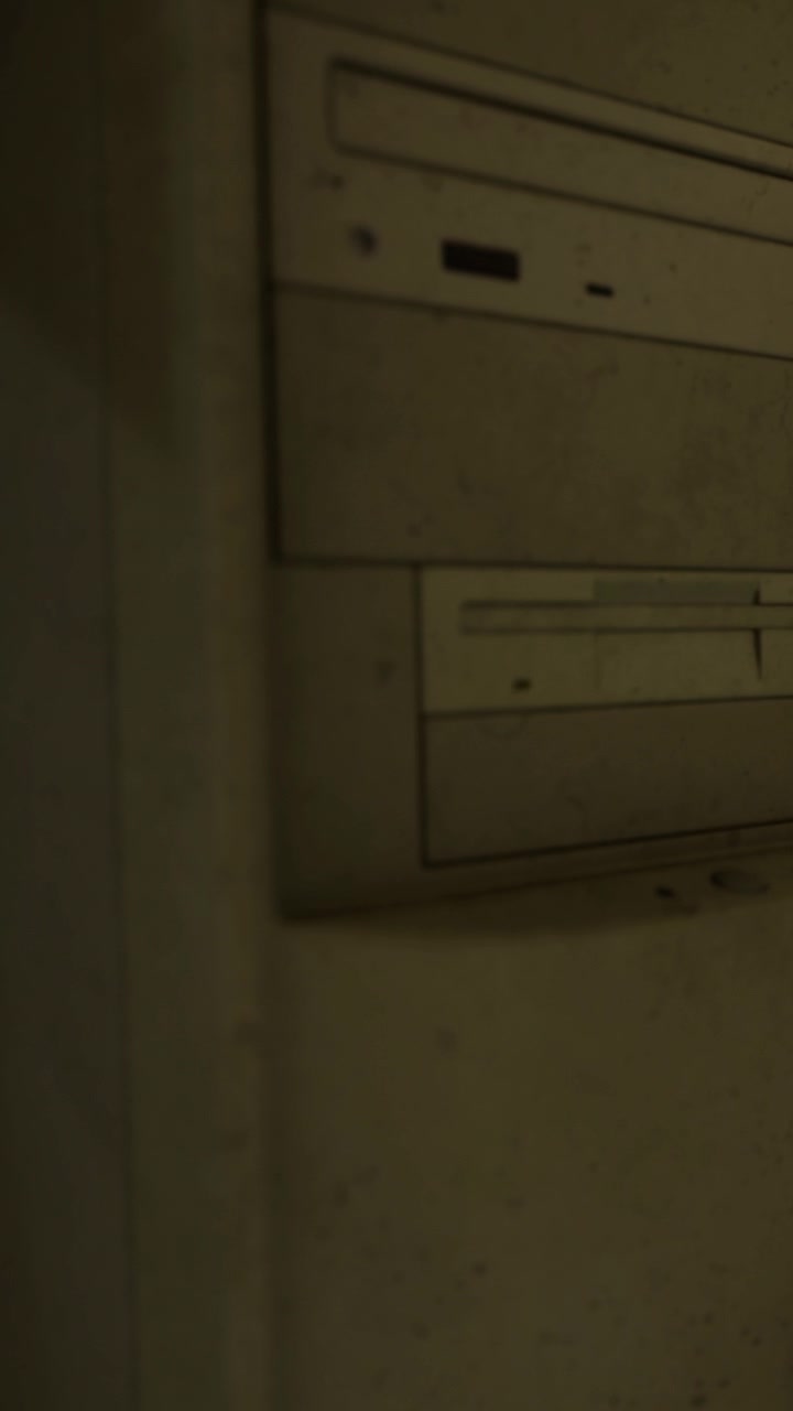 Old computer tower sits against a wall in a dimly lit room