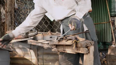 worker sharpening a broad blade with a grinding wheel