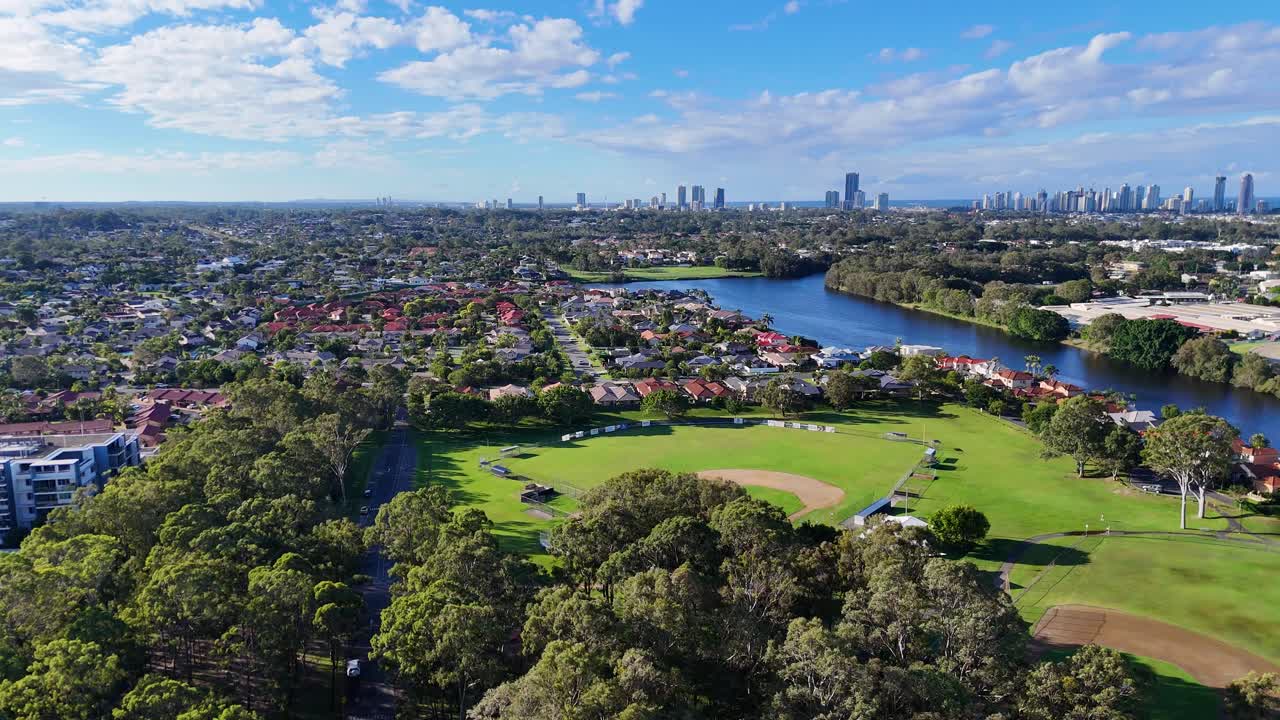 Drone footage captures Gold Coast's lush parkland, winding river, and iconic skyline under clear blue skies