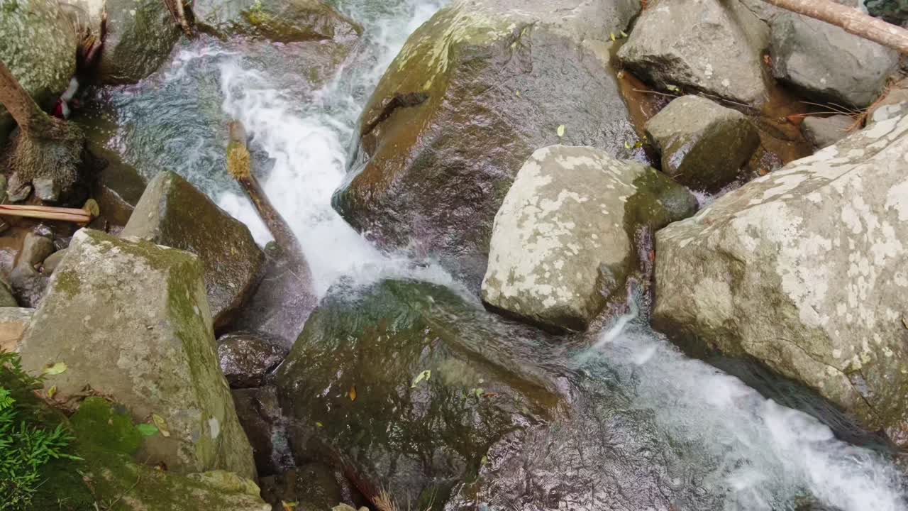 A creek in the Gold Coast Hinterland flows rapidly over rocks, captured in stunning slow motion, highlighting the vibrant white water and natural beauty of the area.