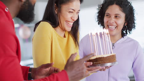 Lachende-Biracial-Frau-Hält-Geburtstagstorte-Und-Feiert-Mit-Verschiedenen-Freunden,-In-Zeitlupe